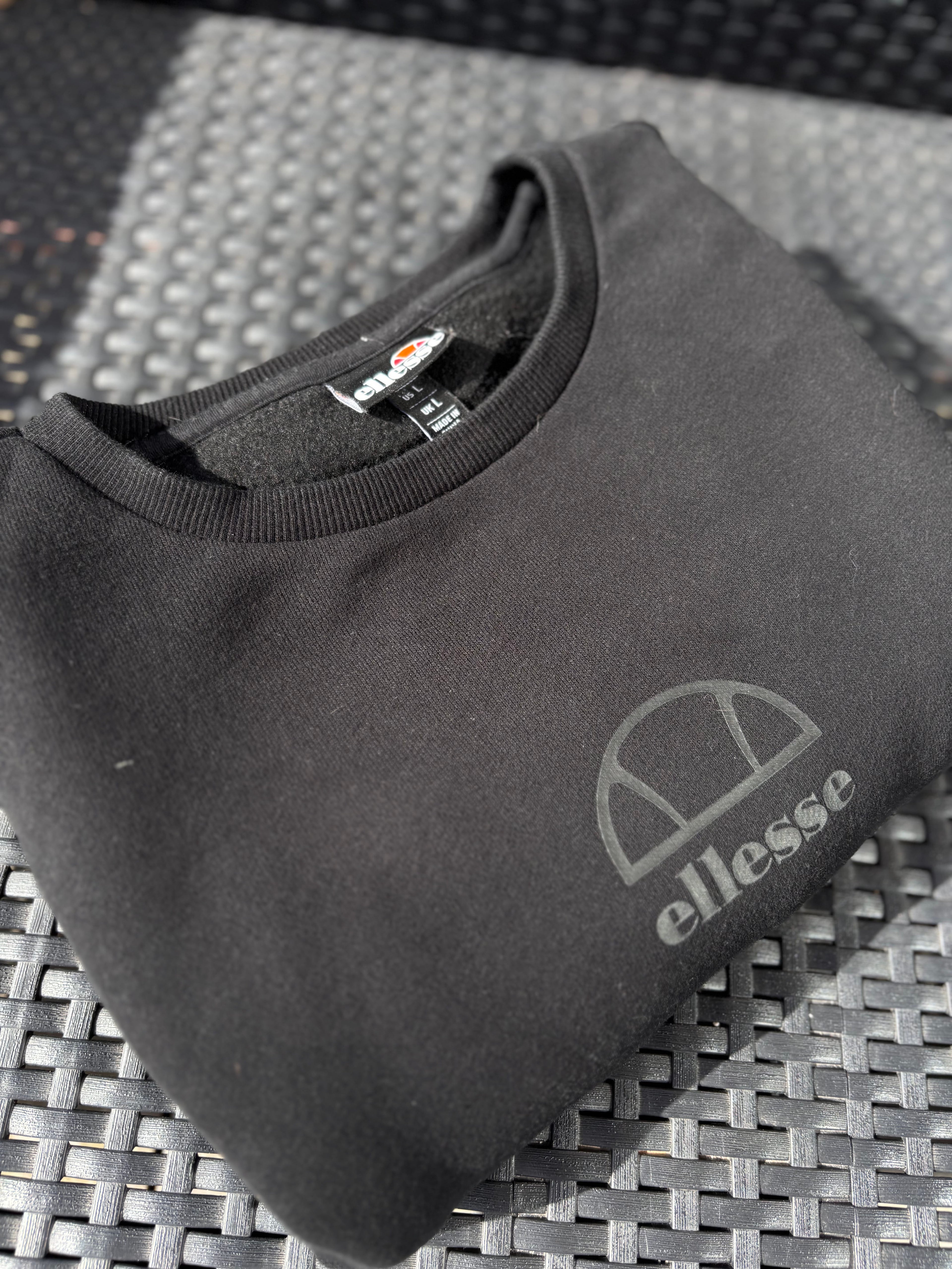 Fabricobe Ellesse sweatshirt med rund hals og logo, blødt bomuldsmateriale, vises i sort farve.